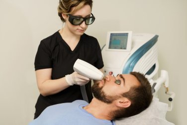 profesional médico sostiene aplicador en el rostro del paciente.