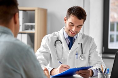 médico con portapapeles hablando con un paciente.