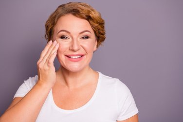 người phụ nữ vui vẻ chạm vào má.