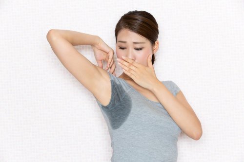 woman revealing wet armpit, covering mouth.