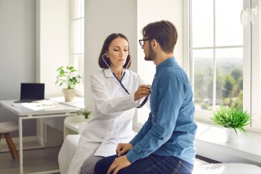 provider with stethoscope listening to patient's chest.