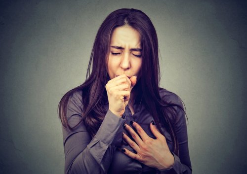 woman coughing, hand on chest.
