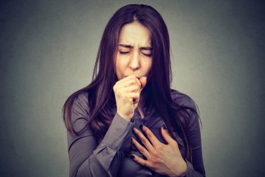 woman coughing, hand on chest.